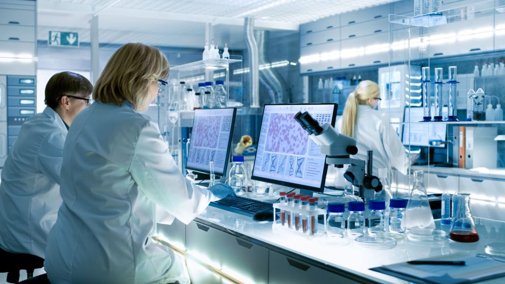 Female and male scientists working on their computers in big modern laboratory.