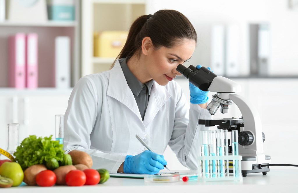 Young female nutritionist testing food samples in laboratory